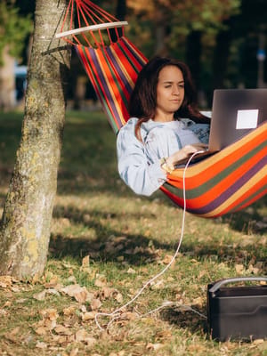 a digital nomad woman working remotely from her hammock as part of her RV office setup